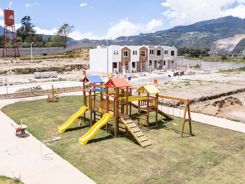 Juegos infantiles sobre césped con el tanque Córdoba y montañas al fondo