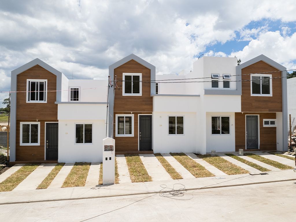 Fachadas de tres casas de madera y blanco con jardineras frente a la calle