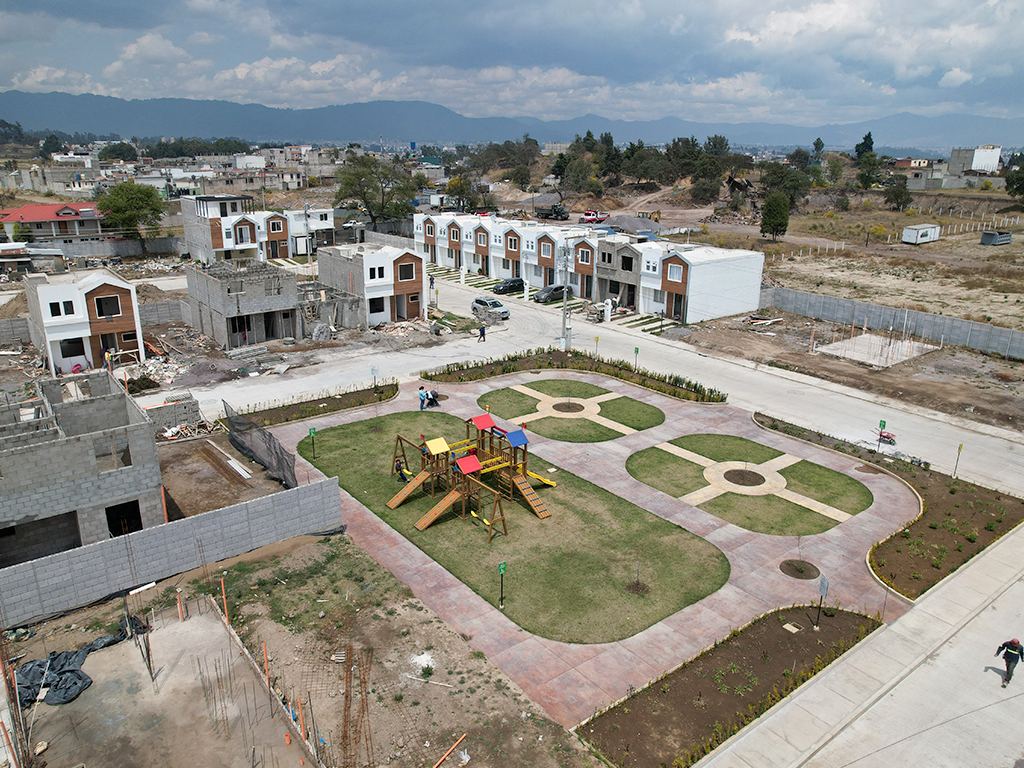 Vista aérea del parque central con juegos, senderos y hilera de casas