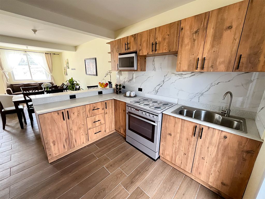 Cocina con gabinetes de madera, estufa, fregadero y backsplash tipo mármol